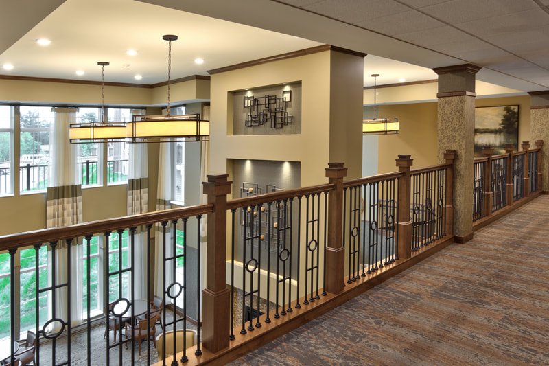 View Looking Down on Two-Story Town Center Lobby With Large Windows Over Wooden Railing